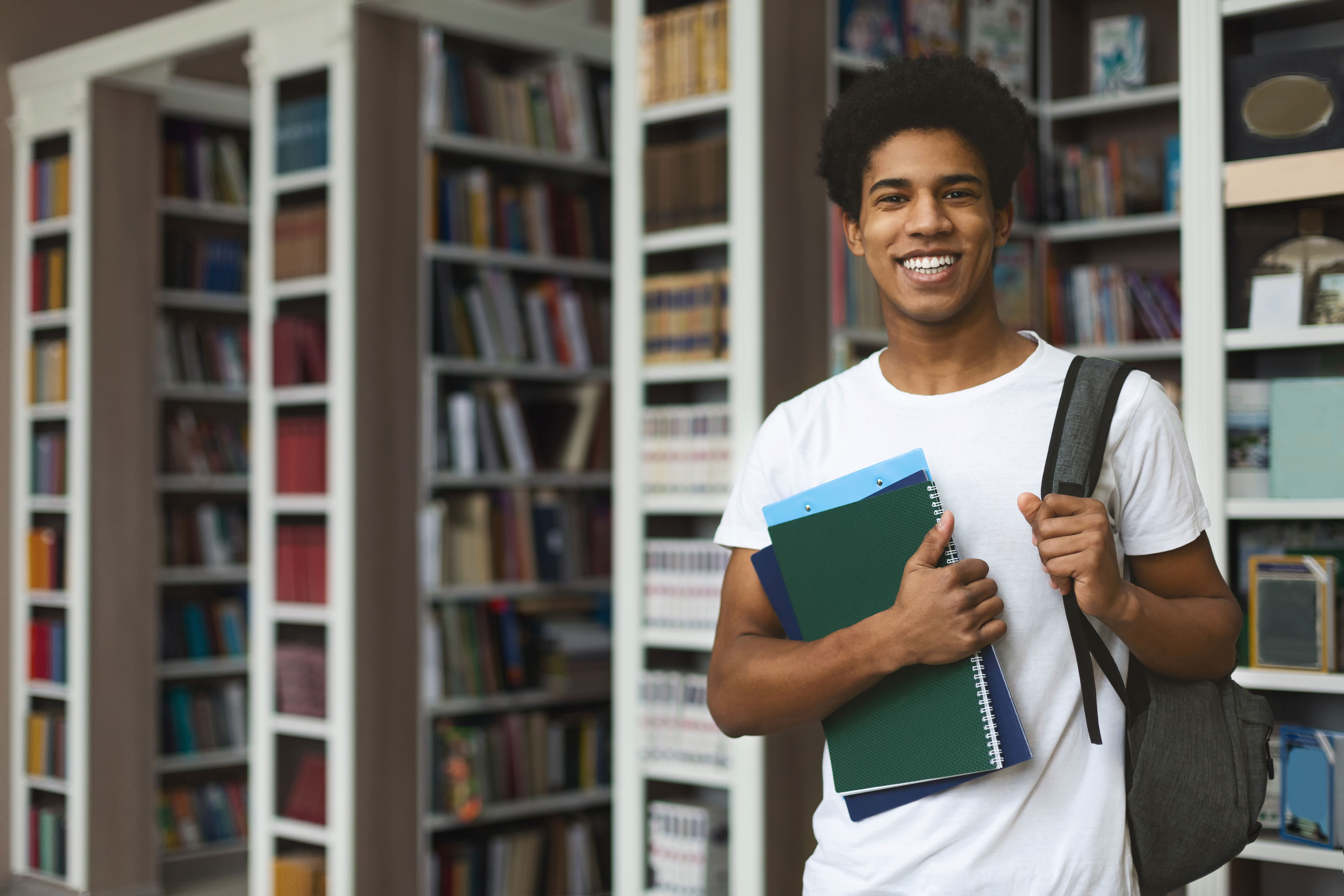 Student holding books and smiling in a library 