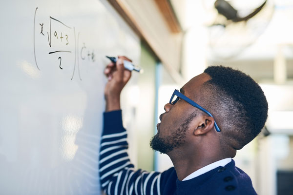 Teacher writing an equation on a white board.